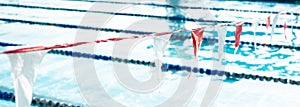 Panorama view public competitive swimming pool near large park, string of backstroke flag hanging over lane divider rope floats,