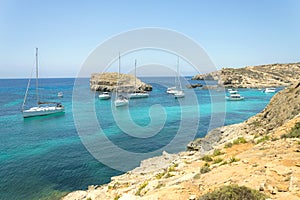 Panorama of sailing boats anchored on open sea in popular bay Blue lagoon on Comino island Malta. Turquoise azure aocean, yachts