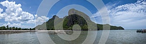 Panorama view of the sea and rock beach with long big mountain and beautiful blue sky, cloud in background