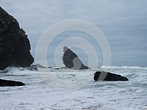 Panorama view of sea stack rock formation cliff at Praia de Adraga rough atlantic ocean coast wind storm Lisbon Portugal