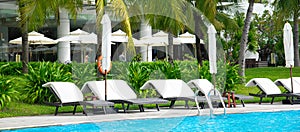 Panorama view upscale multistory resort hotel building with outdoor swimming pool, surrounding lush green coconut palm trees