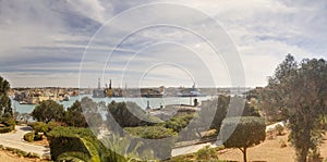 Panorama view of the Valletta city harbor area at Malta, with many historic buildings along the coastline and a red ship