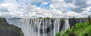 Victoria Falls of Zambezi River, border of Zambia and Zimbabwe with blue sky and dramatic clouds