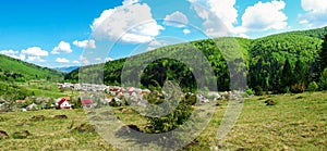 Panorama - village, mountains covered with the green wood and th