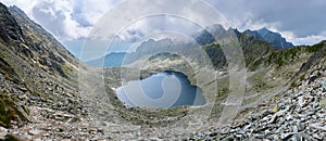 Panorama of Vysne Wahlenbergovo lake in Slovakia High Tatras mountains with fluffy gray clouds. Hiking, trekking, tourism.