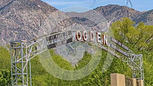 Panorama Welcome arch in Ogden Utah against lush trees towering mountain and blue sky photo