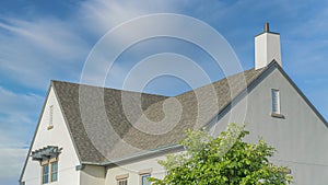 Panorama Whispy white clouds Home exterior with asphalt composite shingle roof and chimney