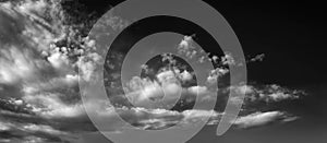 Panorama of white clouds on a dark dramatic sky. Storm wind clouds. Black and white sky template