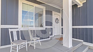 Panorama White porch chairs against window and front door of home with gray exterior wall