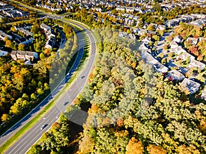 Panorama  winding road along residential quarters of a small town among the autumn forest