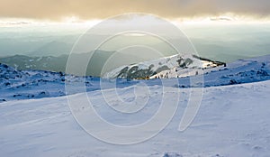 Panorama of winter snowy mountains and sky with sunlit clouds