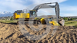 Panorama Yellow construction vehicles at a construction site against mountain and sky