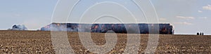 Panoramatic view to stack hay in fire on field with firemans