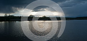 Panorami of dramatic stormy dark sky over the pond at spring, almost monochrome,siluette