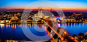 Panoramic aerial night landscape of the gothic catholic Cologne cathedral, Hohenzollern Bridge and the River Rhine in Cologne, Ger