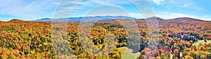 Panoramic aerial over peak fall forest mountains in Vermont with blue skies