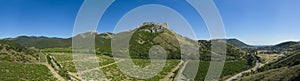 Panoramic aerial view on green grape fields among green hills and mountains, stone rocks