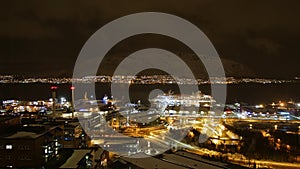 Panoramic aerial view of northern TromsÃÂ¸ by night with illuminated streets and buildings and Aida cruise ship at anchor.