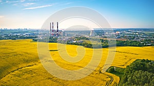 Panoramic aerial view of power plant with golden flowering field of rapeseed