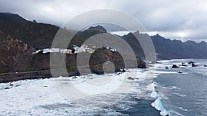 Panoramic aerial view of wild coastline with big waves on the north coast of the island Tenerife, Spain. Little village in the