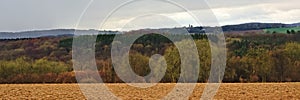 Panoramic Ardennes landscape,with empty winter farmland and forests and hills on a rainy day with dark clouds