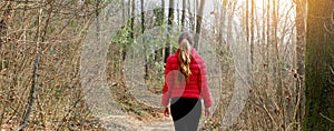 Panoramic banner view of lost woman walking alone on a forest path in autumn or winter