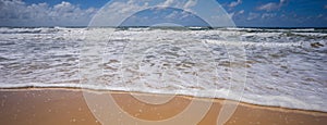 Panoramic beach view with Sand White Surf and Cloudy Sky
