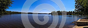 A panoramic of the blue waters of Lake Peachtree with vast miles of lush green trees and boats docked along the lake