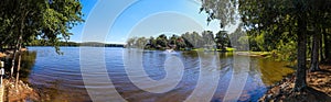 A panoramic of the blue waters of Lake Peachtree with vast miles of lush green trees and boats docked along the lake