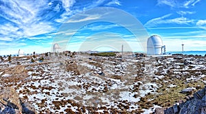 Panoramic of Calar Alto Observatory at the snowy mountain top in Almeria, Andalusia, Spain, 2019. Sky passing through against the