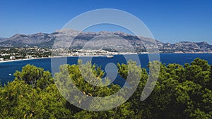 Panoramic coastal view to Atea over mediteranean sea and blurred pines in natural park `Serra Gelada` in Albir, Spain