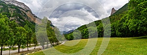 Panoramic green landscape with trees, grass and dark clouds in cloudy summer day in Ordesa Pirineos, Spain photo
