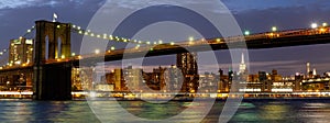 Panoramic image of the Brooklyn Bridge illuminated at night