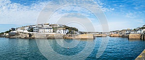 Panoramic image of Porthleven Harbour on a sunny day with a blue sky soft white clouds