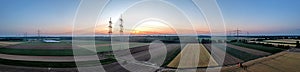 Panoramic image of power line over land during sunset in afterglow