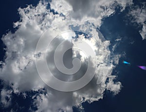 Panoramic image of the sun behind the clouds on the blue sky