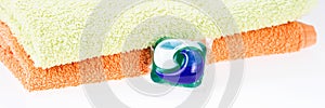 Panorama. Three in one eco gel capsule laundry detergent in front of two towels