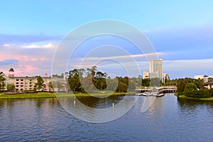 Panoramic l view of Victorian style Hotel and Boat Launch on colorful sunset sky background at Lake Buena Vista