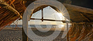 Panoramic landscape background panorama of . Hut with thatched roof in Hawaiian look made of straw on the beach at sunset -