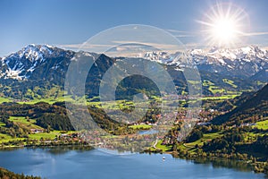 Panoramic landscape with lake aund mountainrange against sky with sun