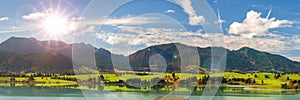 Panoramic landscape with lake aund mountainrange against sky with sun photo