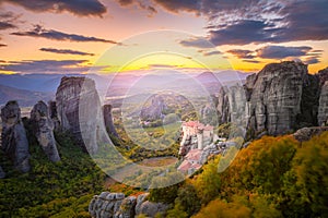 Panoramic landscape of Meteora, Greece at romantic sundown time with real sun and sunset sky. Meteora - incredible sandstone rock