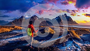 Panoramic landscape at sunrise. Backpacker standing at Vestrahorn mountains in Stokksnes, Iceland photo