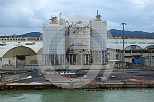 Panoramic landscape view of commercial docks with silos and warehouses in port of Livorno. Import, export and business logistic.
