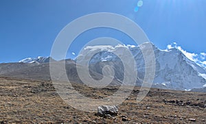 Panoramic landscape view of rocky barren land with distant snowcapped great Himalayas mountain range on a winter day in North
