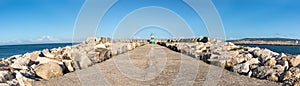 Panoramic of lighthouse at the end of the asphalt road at sea