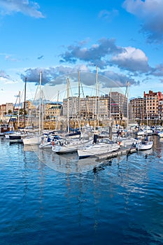 Panoramic marina with many small sailing boats docked on the shore of the city of Gijon, Asturias, Spain.