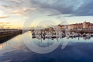 Panoramic marina with many small sailing boats docked on the shore of the city of Gijon, Asturias, Spain.