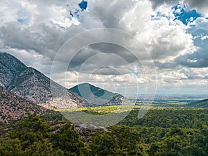 Panoramic mountain valley view with dramatic clouds and green forest