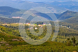 Panoramic mountains view with village and shadow of clouds on green forest valley. Carpathian mountains in perspective.